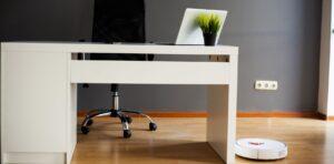An office desk and chair, laptop and robot vacuum cleaner